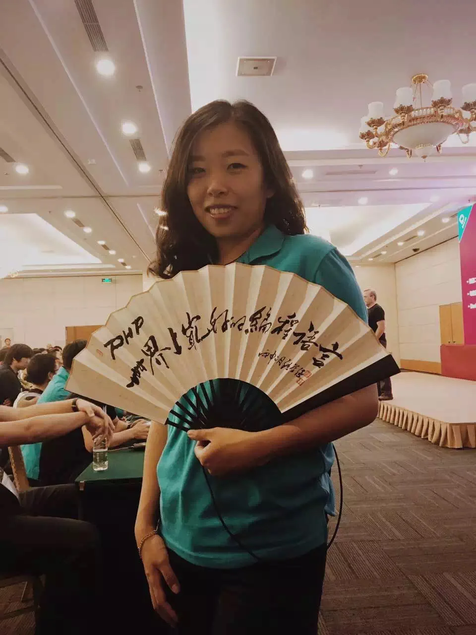 PHPCon 负责人胡姝琦手持折扇，正面书法清晰可见
