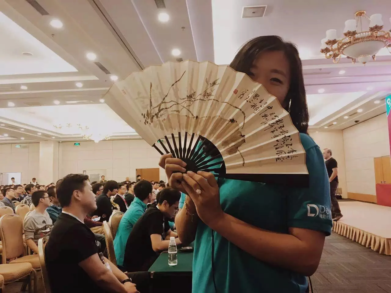 PHPCon 负责人胡姝琦手持折扇，展示扇面背面的水墨画