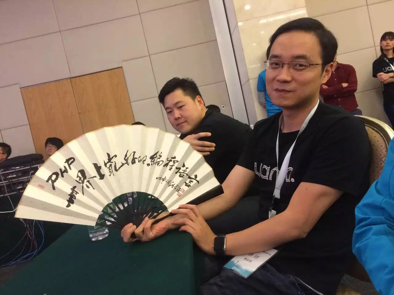 鸟哥拿着折扇并展示上面写着：PHP 世界上最好的编程语言