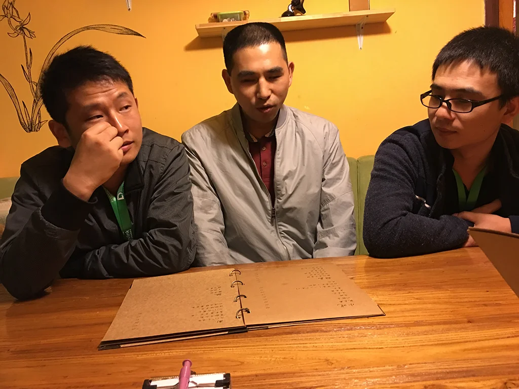 杨永全（中）与同事在餐厅，桌上摆着一本菜单