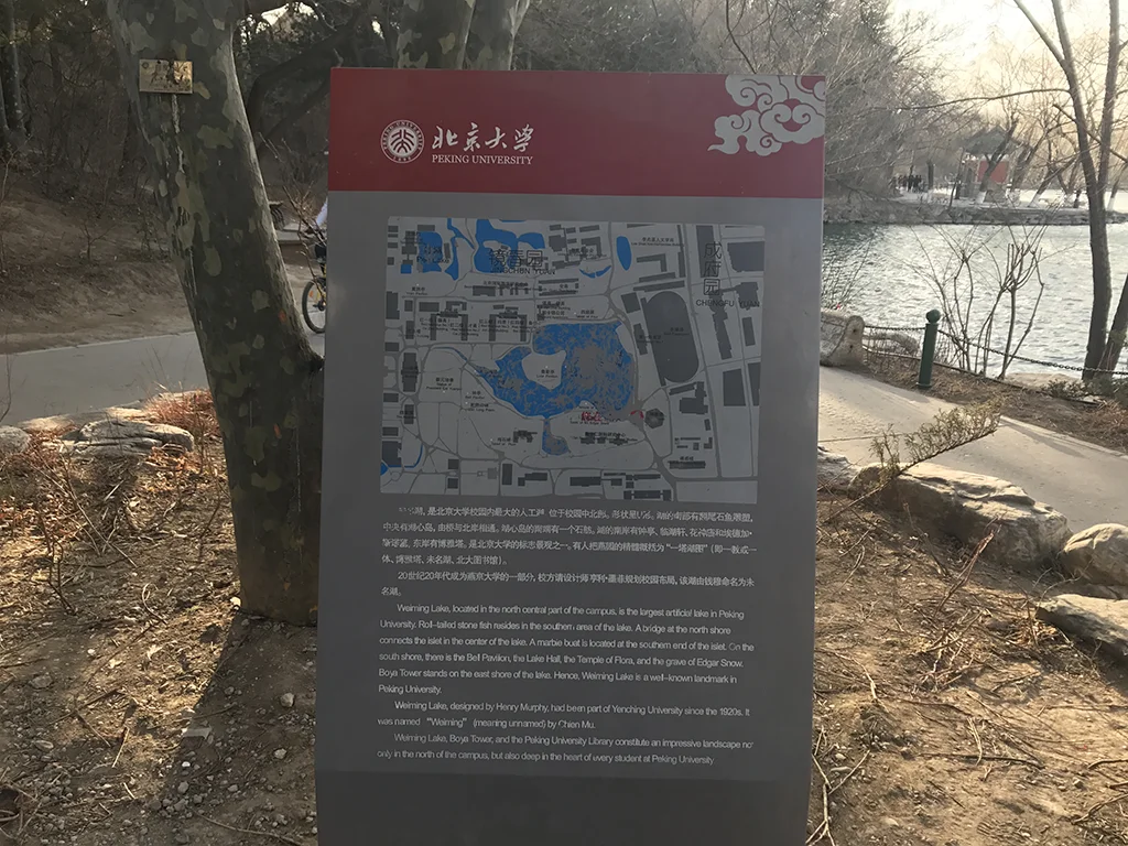 北京大学未名湖景区介绍牌，湖边树木与湖面